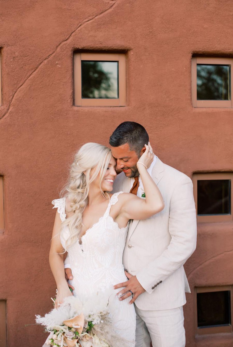 Bride and groom pose in front of red wall