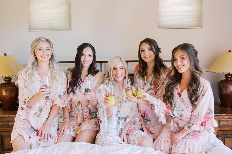 Bridesmaids posing with bride and wearing fancy bathrobes