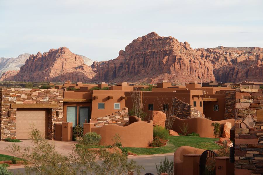 Exterior of The Inn at Entrada with desert landscaping and red rock cliffs in the background in St. George, Utah
